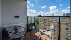 A balcony with two wicker chairs, a small round table, and a GREE air conditioning unit. - Warsaw Wola Studio - Balcony & Workspace -by Rentujemy (Warszawa)