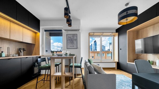 A modern kitchen with a dining area, a sofa, and a TV. - Warsaw Wola Studio - Balcony & Workspace -by Rentujemy (Warszawa)
