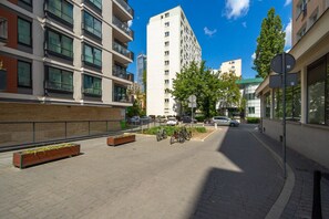 A modern urban street with multi-story buildings, a paved sidewalk, and parked bicycles.