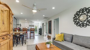 A spacious living area with a sofa, coffee table, and a dining area with chairs and a kitchen in the background. - Vibrant North Palm Beach Home ~ 2 Mi to Beach! (North Palm Beach)