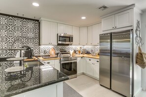 Une cuisine moderne avec des armoires blanches, des appareils en acier inoxydable et un dosseret décoré.