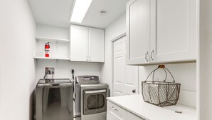 A laundry room with a washing machine, dryer, and a fire extinguisher on the wall. - Vibrant North Palm Beach Home ~ 2 Mi to Beach! (North Palm Beach)