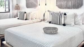 A modern bedroom with two beds, macramé wall hangings, pendant lights, and a view of greenery outside. - Studio Yuca - at Loreto 80 downtown  (Loreto)