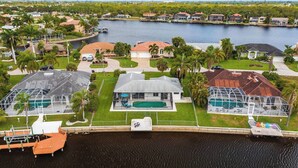 A residential area with houses, a dock, and a large body of water. - Waterfront Villa: Gulf Access Canal,  Dog Friendly, Heated Pool (Cape Coral)
