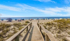A wooden boardwalk leading to a beach with umbrellas and beach chairs. - Perdido Dunes 21 (Orange Beach)