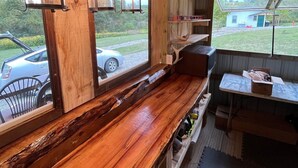 A rustic wooden interior with a long bench and table, large windows, and hanging lanterns. - OSU Camper/RV (New Lexington)