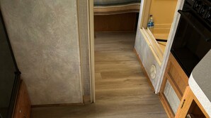 A compact kitchen with wooden cabinets, a built-in oven, and a microwave. - OSU Camper/RV (New Lexington)