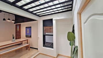 A room with a skylight, a bench, a potted plant, and a door.