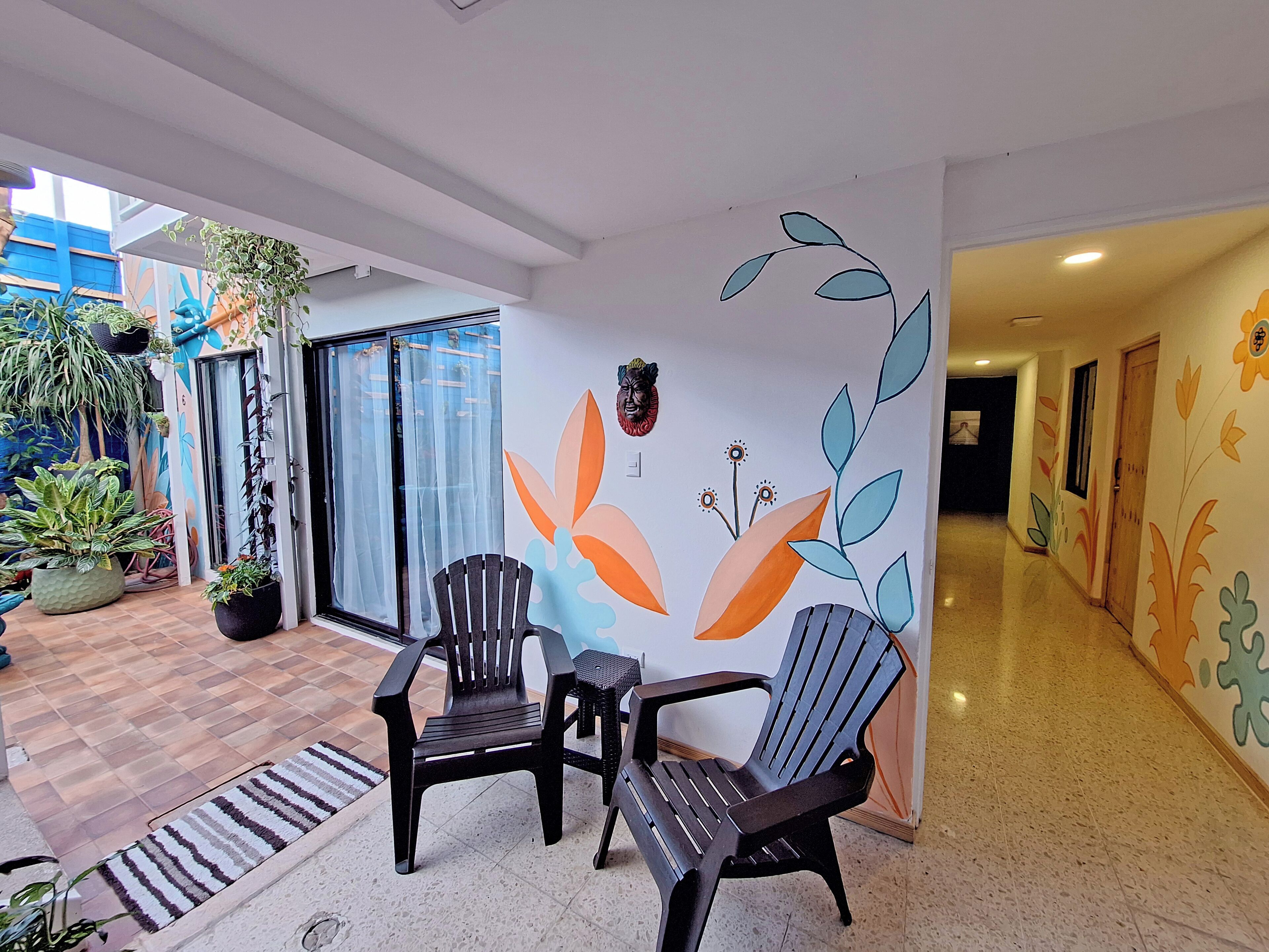 Ein Hotelkorridor mit modernem Design, der sich durch eine Wand mit floralen Mustern und eine zur Zimmerführende Tür auszeichnet.