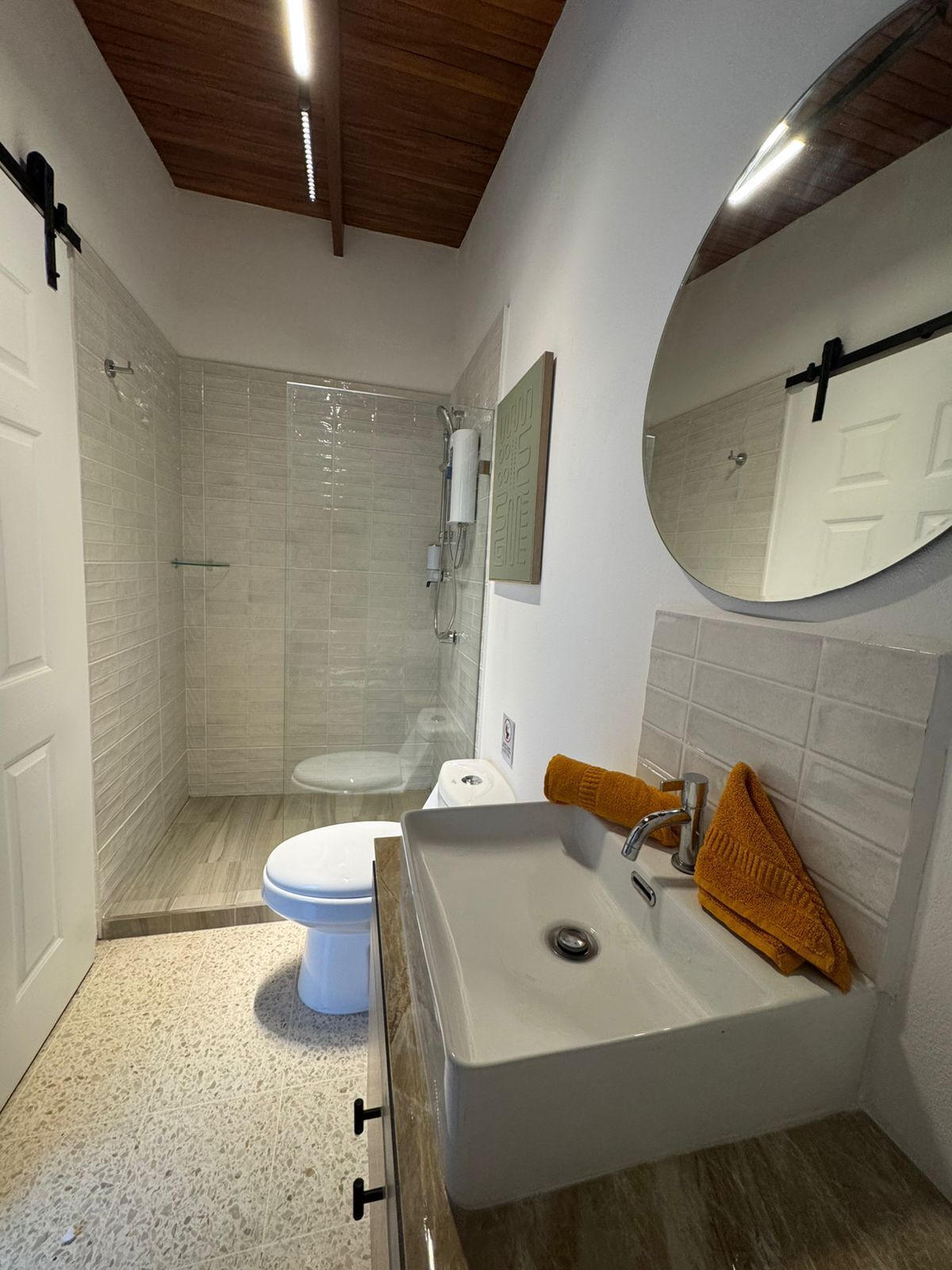 A modern bathroom with a shower, toilet, and sink.