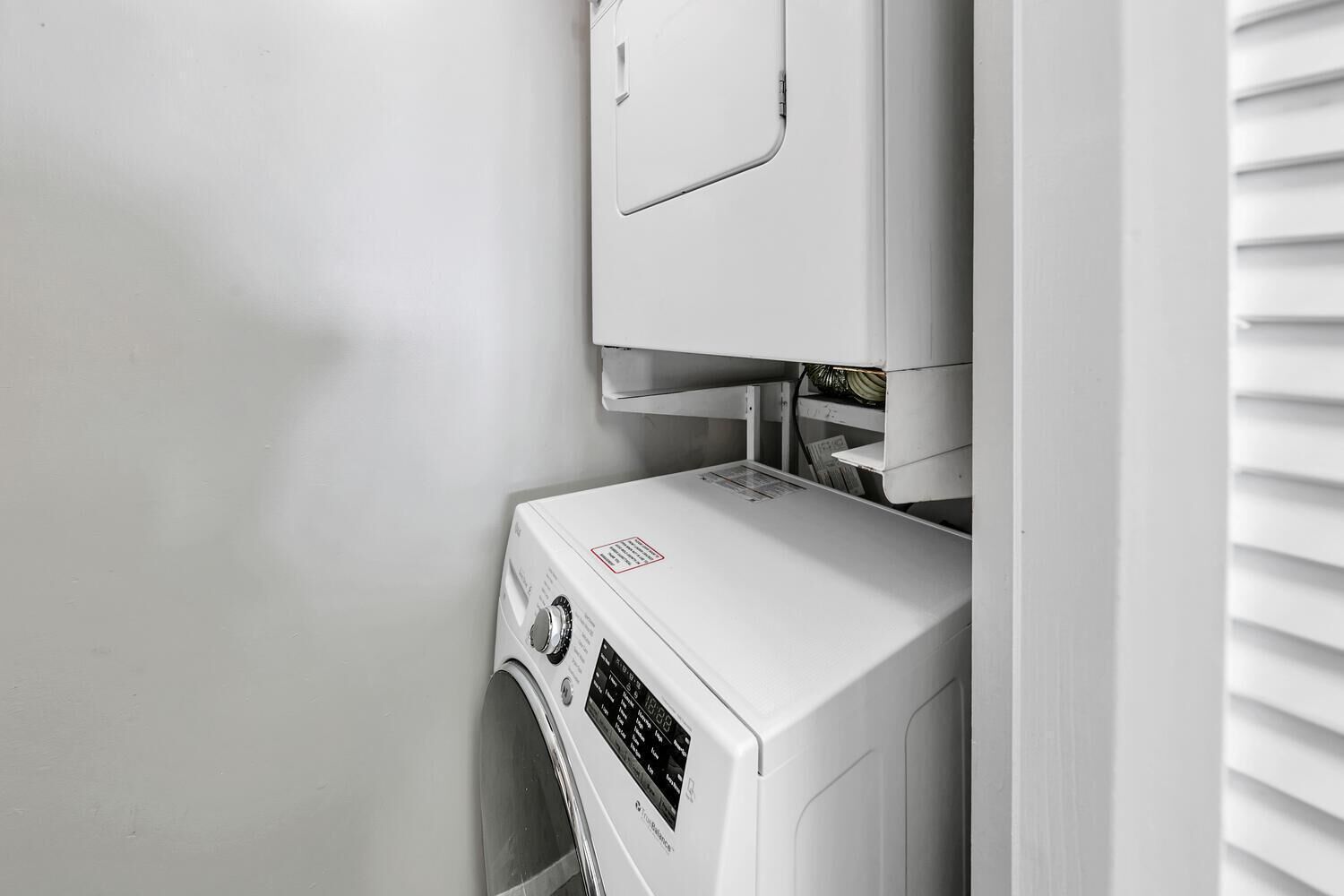 A compact, white, wall-mounted washer and dryer unit with a control panel and a small window.