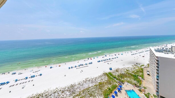 Blick auf den Strand vom Hotelbalkon mit Pool und Strandliegen.
