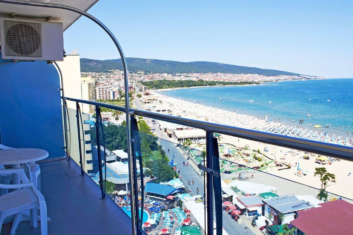 Ein Balkon mit Blick auf einen Strand, einem Tisch und Stühlen.