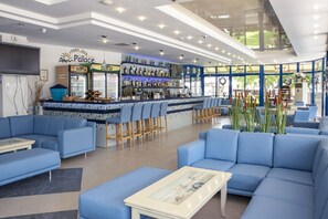 A modern lobby with blue seating, a bar area, and a large window offering a view of the outdoors.