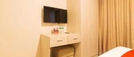 A hotel room with a bed, a bedside table with a TV, a wardrobe, and a curtain.