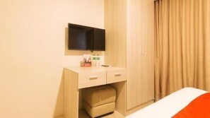 A hotel room with a bed, a bedside table with a TV, a wardrobe, and a curtain.