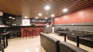 Un ristorante con un'area bar, posti a sedere e un bancone.