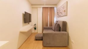 Un soggiorno moderno e accogliente con un divano grigio, una TV a schermo piatto montata sulla parete e un quadro sopra il divano.