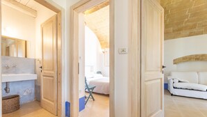 A room with a bathroom, a bed, and a white sofa.
