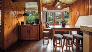 A wooden interior with a kitchen area, bar stools, and a window overlooking greenery. - Lujosa Cabaña Privada En Valle de Bravo (Valle de Bravo)