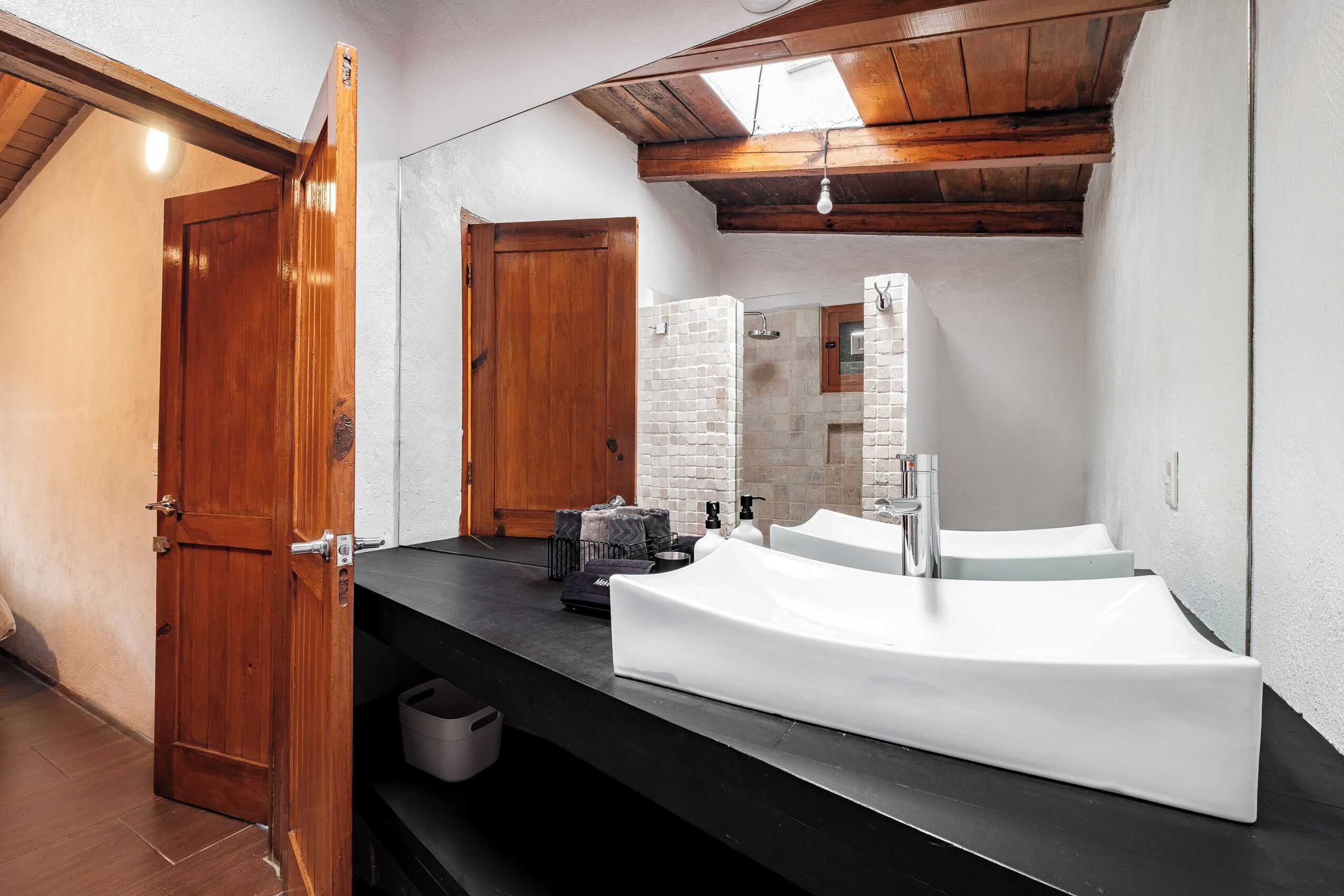 A bathroom with a large mirror, a white sink, and a wooden door.