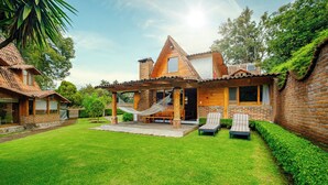 A house with a brick exterior, a covered porch, a hammock, and two lounge chairs. - Lujosa Cabaña Privada En Valle de Bravo (Valle de Bravo)
