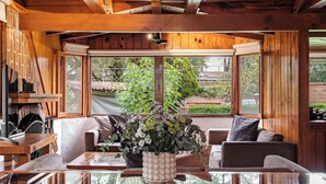 A wooden interior with a dining table, chairs, and a sofa. There is a window with a view of greenery outside. - Lujosa Cabaña Privada En Valle de Bravo (Valle de Bravo)