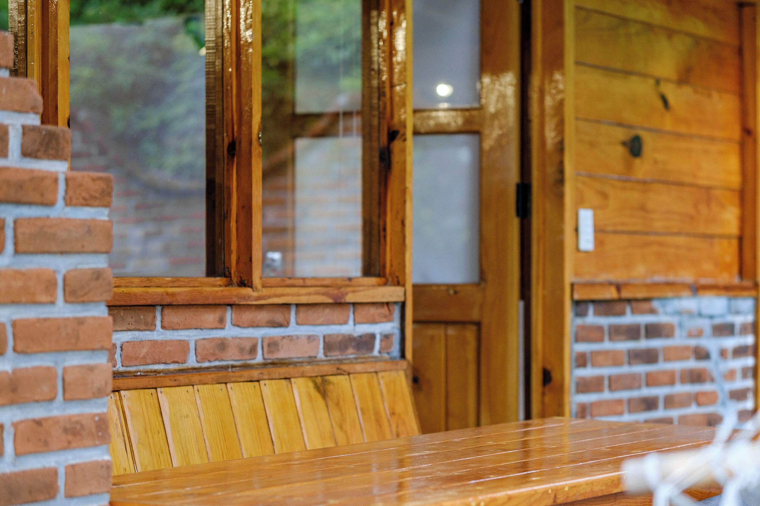 A wooden bench with a brick wall and a wooden door in the background.