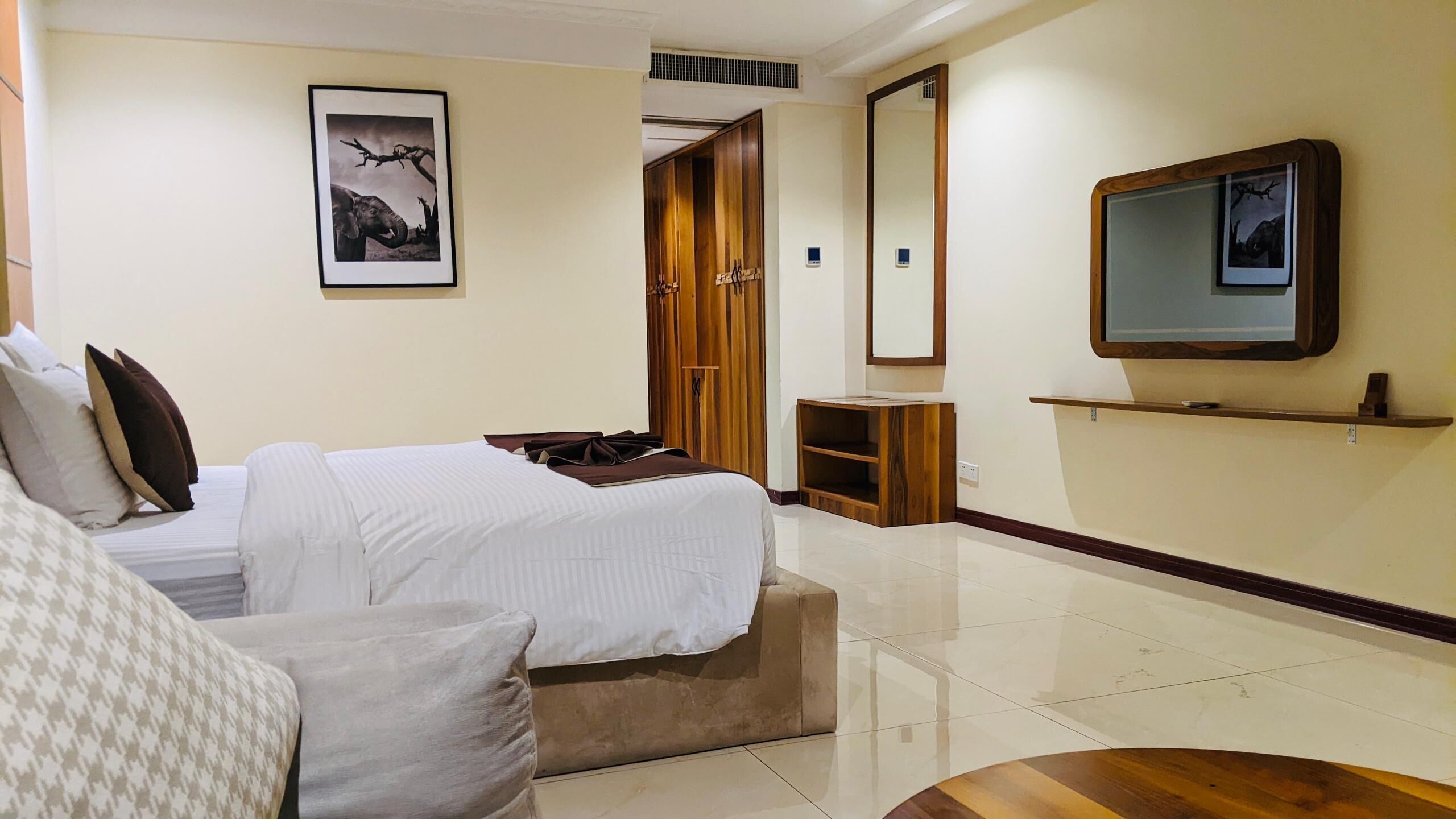 A hotel room with a bed, a bedside table, a mirror, and a wardrobe.