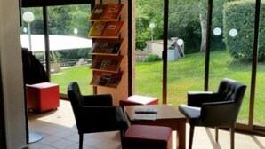 Een kamer met een groot raam, een boekenkast en een rode stoel.