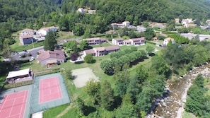 Vogelperspectief van een woonwijk met huizen, een tennisbaan en een rivier.