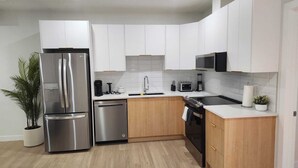 A modern kitchen with white cabinets, stainless steel appliances, and a wooden countertop. - Deluxe 2-BR Basement Suite in South East Calgary (Calgary)