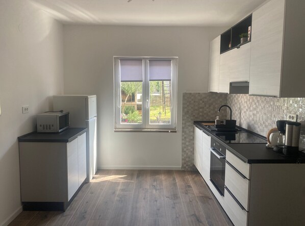 A compact kitchen with a window, a refrigerator, a sink, and a stove. - Apartments Danijela & Vlado (Lopar)