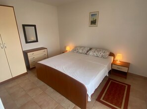 A bedroom with a bed, two bedside tables with lamps, a wardrobe, a mirror, and a framed picture on the wall. - Apartments Danijela & Vlado (Lopar)