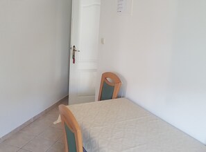 A room with a single bed, a chair, and a door. - Apartments Danijela & Vlado (Lopar)