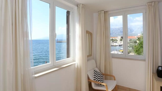 Een kamer met uitzicht op zee en een stoel met een zwart-wit kussen.