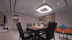 A modern dining area with a table and chairs, a ceiling light, and a cityscape painting on the wall. - Yunfu Jinyu Hotel (Yunfu Bus Station Yihua International Plaza) (Yunfu)