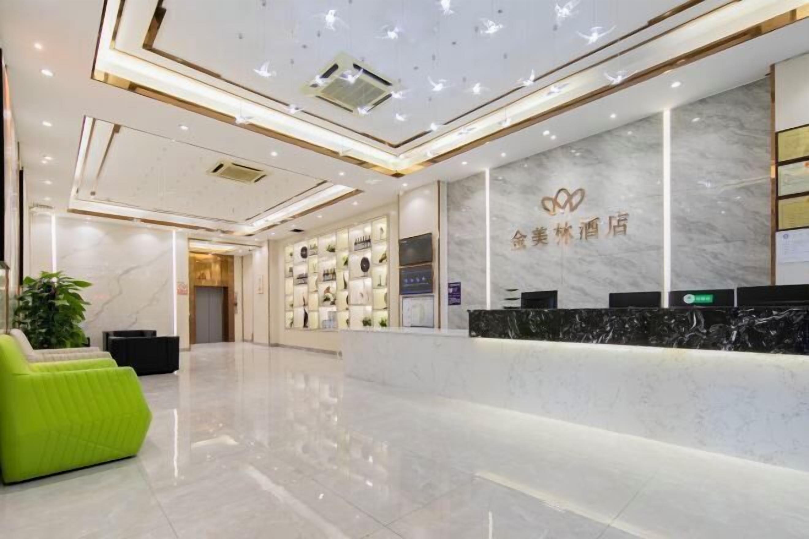 A hotel reception area with a marble reception desk, a green seating area, and a wall displaying various amenities.