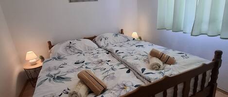 Una cama bien hecha con ropa de cama floral, dos lámparas de noche y un cuadro en la pared.