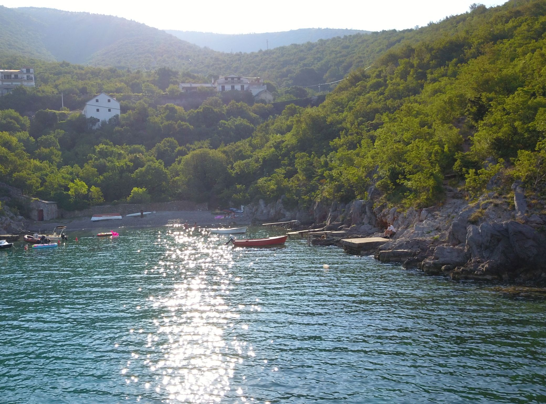 Une zone côtière avec des bateaux, une côte rocheuse et des bâtiments en arrière-plan.