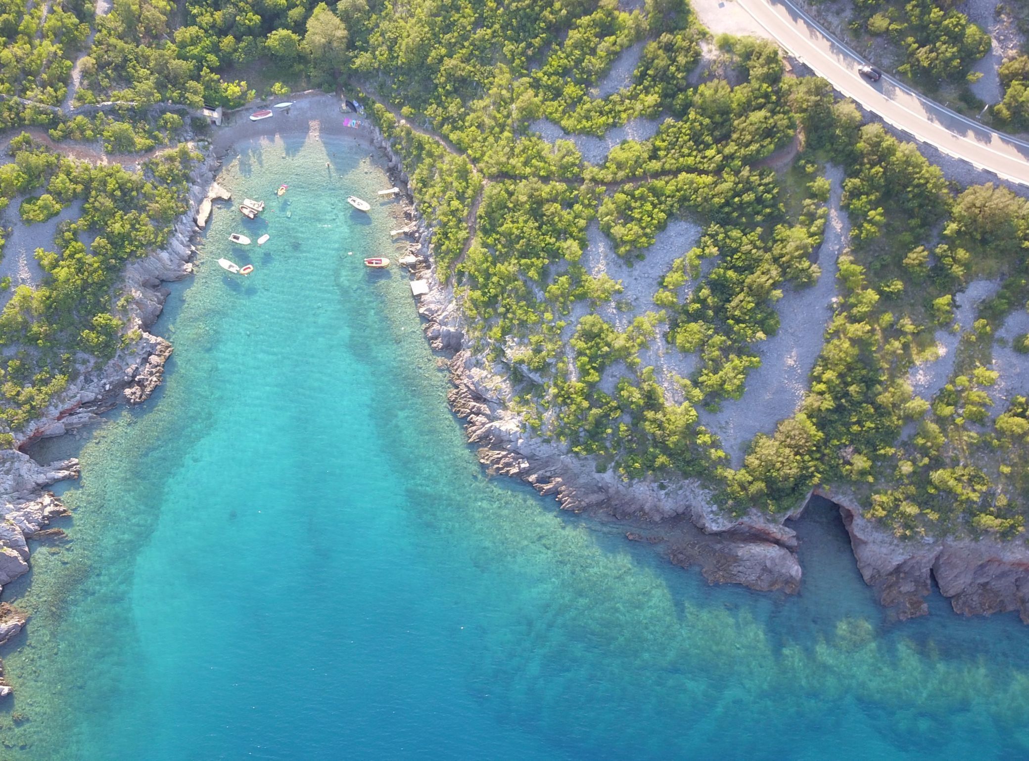 Vista aérea de una zona costera con aguas turquesas cristalinas, costas rocosas y vegetación verde exuberante.