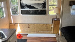 A compact RV interior with a kitchen area, a bed, and a scenic view through the windows. - Big spacious Camper (New Lexington)