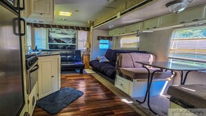 A compact RV interior with a kitchenette, seating area, and a small table. - Big spacious Camper (New Lexington)
