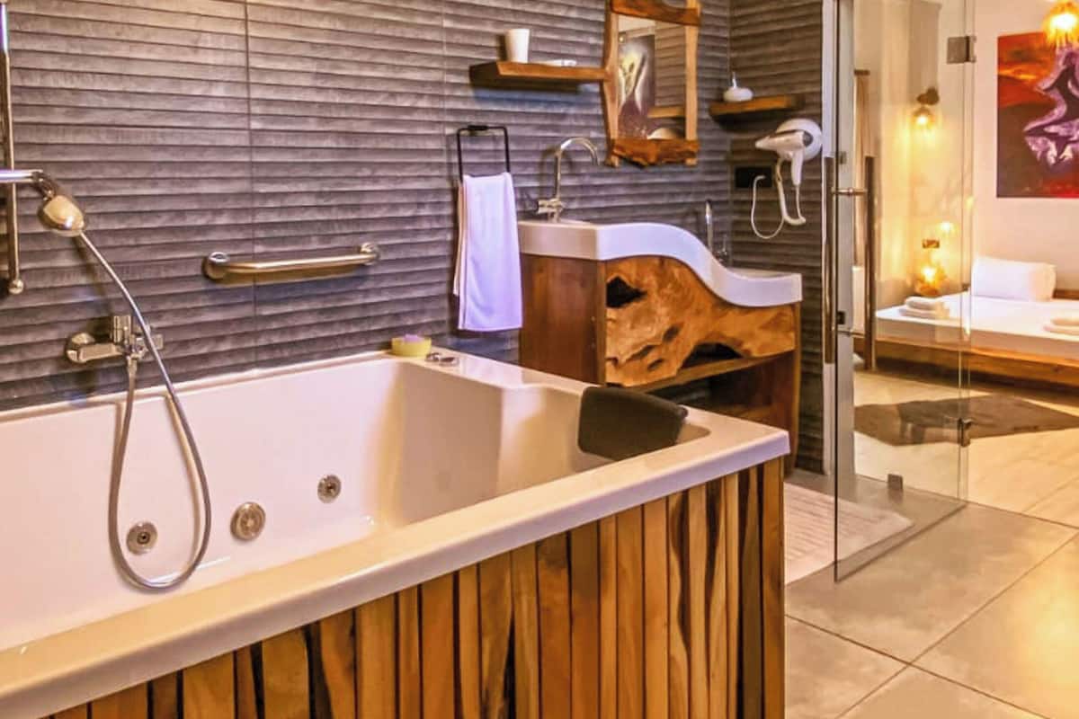 A modern bathroom with a large bathtub, wooden paneling, a glass shower enclosure, and a wooden vanity with a sink.