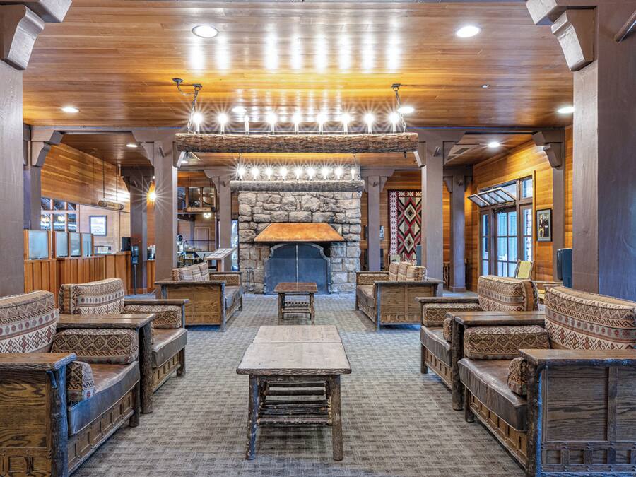 A spacious lobby with a stone fireplace, wooden furniture, and a high ceiling with recessed lighting.
