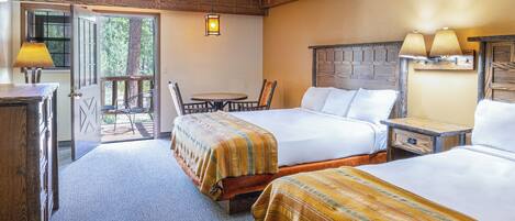 A hotel room with two beds, a wooden headboard, a small table, and a chair.