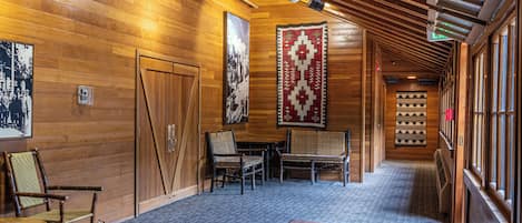 Un pasillo con paredes de madera, suelo alfombrado y un banco. Hay puertas y una alfombra grande.
