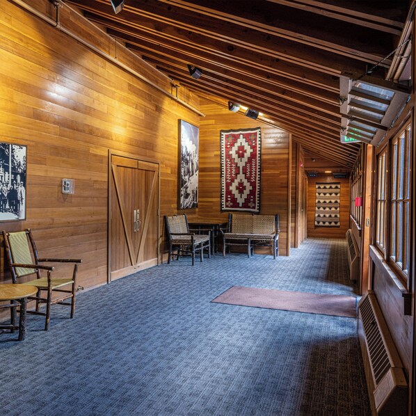 A hallway with wooden walls, a carpeted floor, and a bench. There are doors and a large rug. - The Lodge at Bryce Canyon (Bryce Canyon)