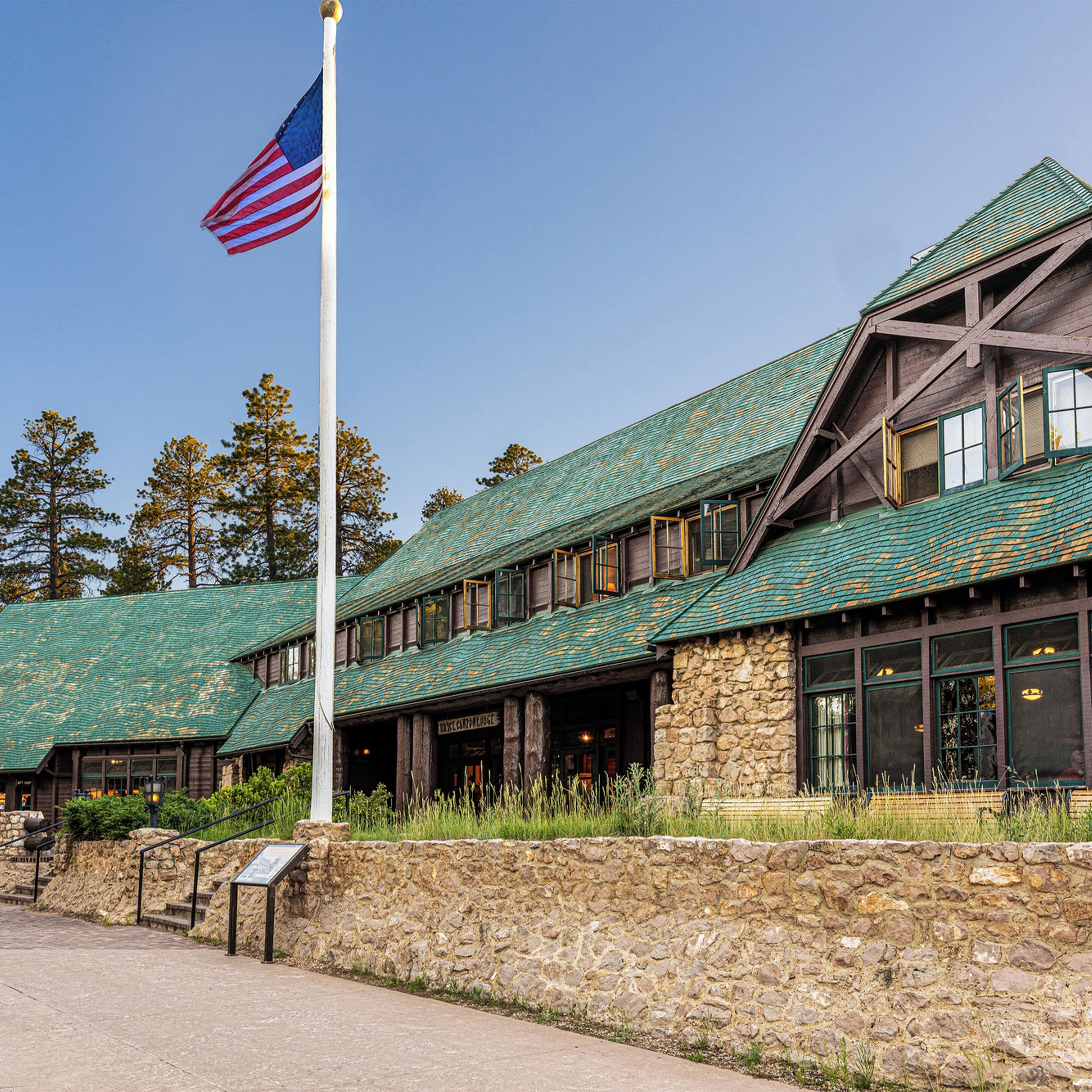 A lodge with a stone facade, green roof, and large windows.