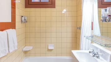 Een badkamer met een bad, douche, wastafel en spiegel.
